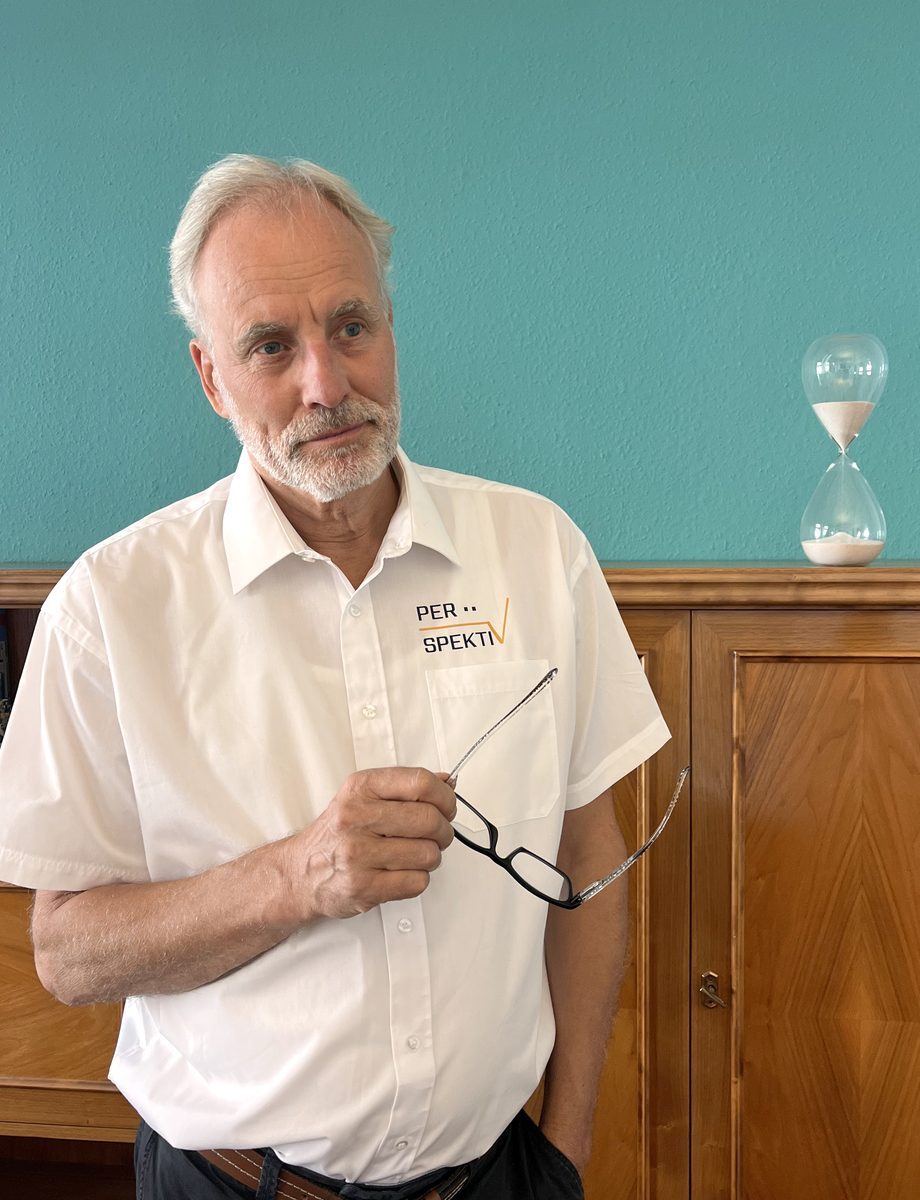 Ulrich Freund blickt nachdenklich auf eine Sanduhr im Büro in Chemnitz